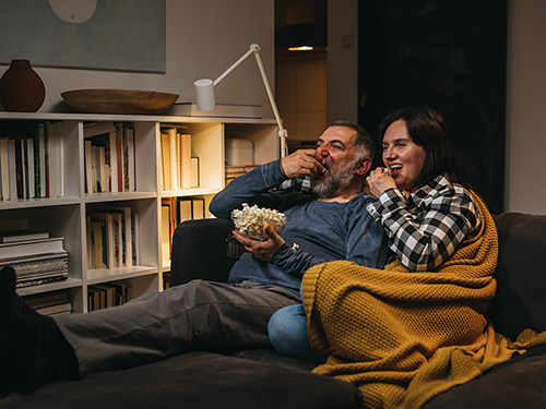 Couple staying warm inside watching a movie with popcorn>